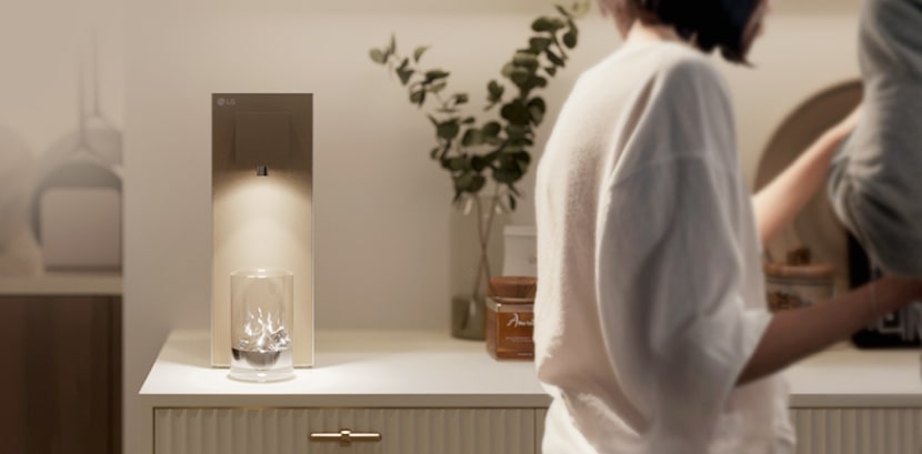 LG water purifier in lifestyle settings with a woman stainding in front of the purifier.