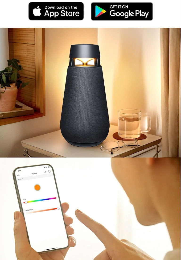 The XBOOM 360 Speaker on a table beside a cup of tea and a pair of glasses while a person controls the color of the light on the speaker from their phone.