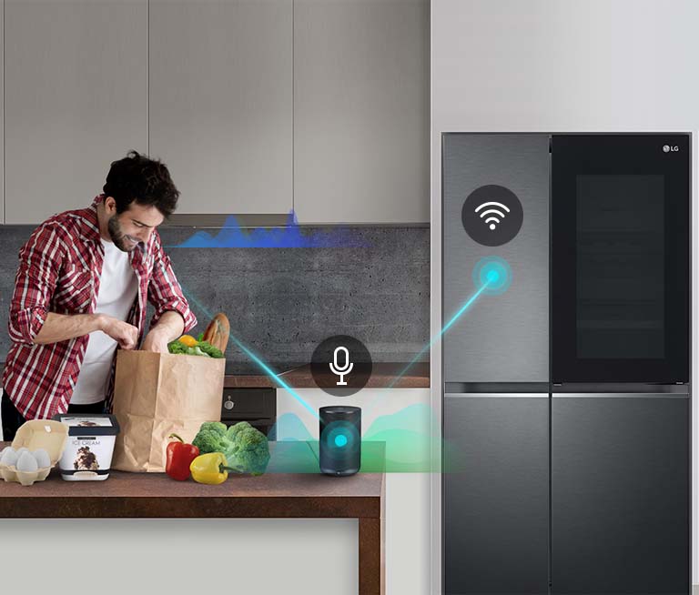 A man stands in a kitchen unloading produce from a grocery bag and speaks, shown by volume bars moving up and down near him, to the AI speaker on the counter telling it to "turn on express freeze". A line appears that goes from the man to the AI speaker which has a microphone icon above it. Then volume bars show up near the AI speaker and a line appears from the AI speaker to the refrigerator which has a Wifi icon above it.