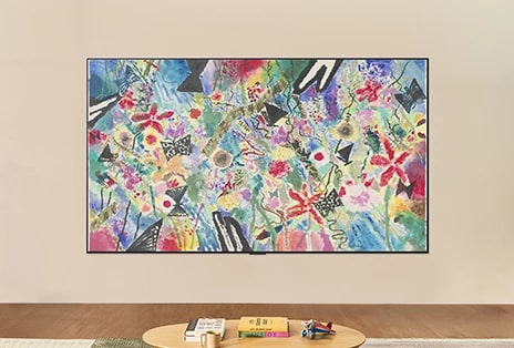 LG ART TV is wall-mounted in a bright room, showing a colorful floral-and-fruit artwork in Gallery Mode while brightness control adjusts for optimal viewing in any light.