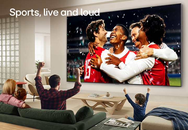 LG Ultra Big TV wall-mounted in a bright living room shows a stadium sports celebration with vivid colors and refined picture quality on a wide screen, while a family seated on sofas cheers together.