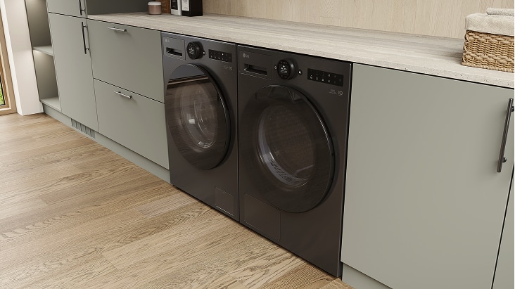 LG black washer and dryer set, built under a light countertop within neutral cabinetry on wood flooring with a clean layout.