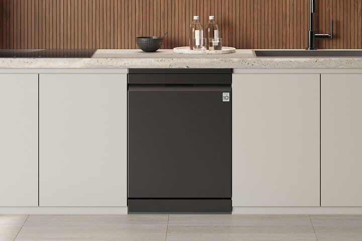 LG Integrated Dishwasher with seamless built-in panel design installed flush between white base cabinets beneath a stone countertop, centered below a wood slat backsplash with sink, bottles, and bowl arranged on the counter.
