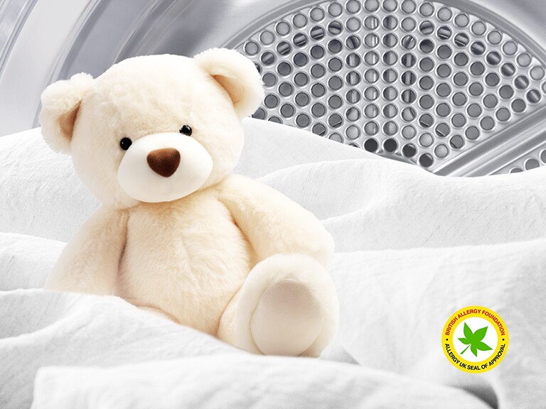 Afbeelding van een deken en een teddybeer in een LG-droger met het logo van de British Allergy Foundation zichtbaar