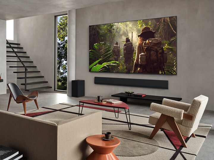 Groothoekbeeld van een woonkamer in een premium woning; een stel kijkt naar een film op hun aan de muur gemonteerde LG OLED TV. Het ontwerp van de tv past elegant bij de muur en het interieur.