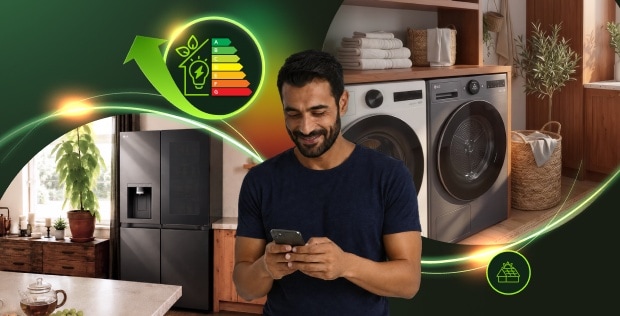 Een man glimlacht terwijl hij naar zijn smartphone kijkt, met op de achtergrond een LG-koelkast, wasmachine en droger, samen met pictogrammen voor energie-efficiëntie en zonne-energie.