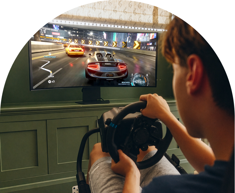 Student geniet van een racegame op een LG UltraGear gamingmonitor met een racestuur.