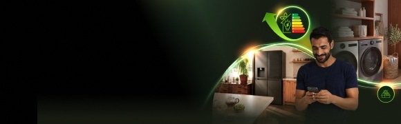 Een man bekijkt op zijn smartphone de energiezuinige huishoudelijke apparaten van LG in een moderne woning, met een koelkast, wasmachine en een pictogram voor energie-efficiëntie.