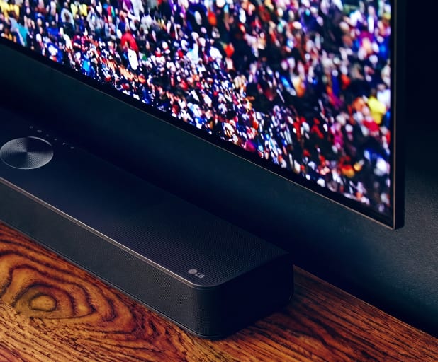 Close-up van een soundbar onder een tv op een houten meubel.