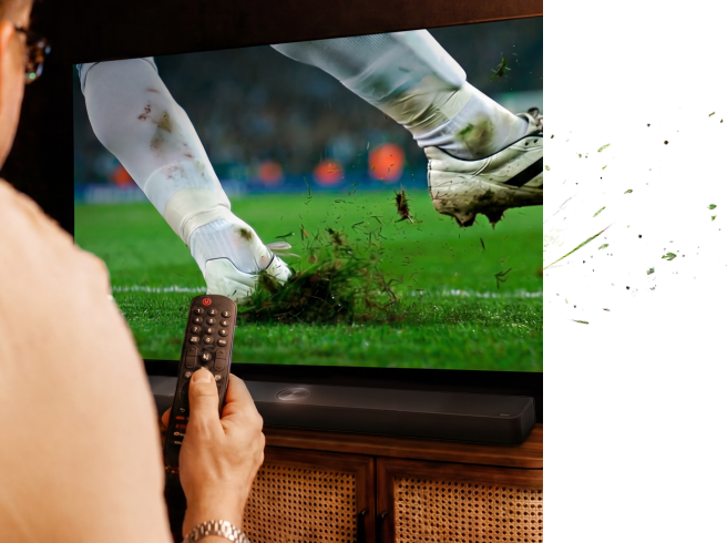 Een hand die een afstandsbediening vasthoudt tijdens het kijken naar voetbal op tv