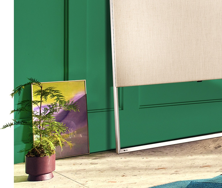 Close-up van EASEL op de vloer, leunend tegen de wand, samen met een schilderij en decoratieve plant.