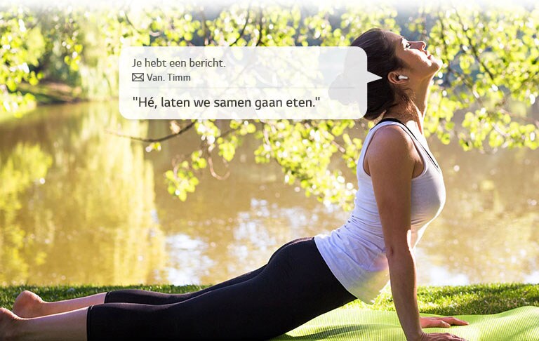 Een vrouw strekt zich uit en leunt naar beneden om de grond te raken terwijl ze luistert naar een boodschap die haar oordopjes voor haar lezen.
