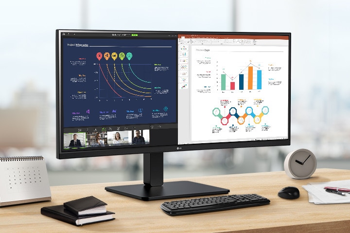 A WQHD IPS monitor is on the desk, displaying a video conference and various graphs on the screen.
