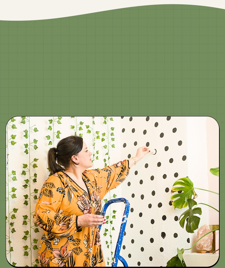De vrouw schildert stippen op de muur.	