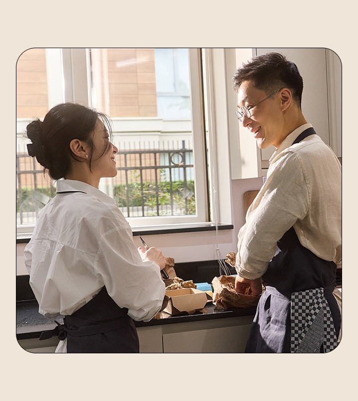 Een man en een vrouw kijken elkaar aan terwijl ze in de keuken koken.