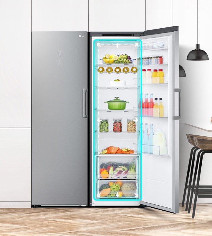 The front view of the fridge is shown in a kitchen with the door open and displaying the produce inside. A blue square highlights the interior with arrows pushing out to indicate there is ample room inside.	