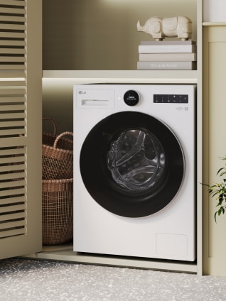 In the laundry room, a white LG washing machine is enclosed in a beige storage cabinet.