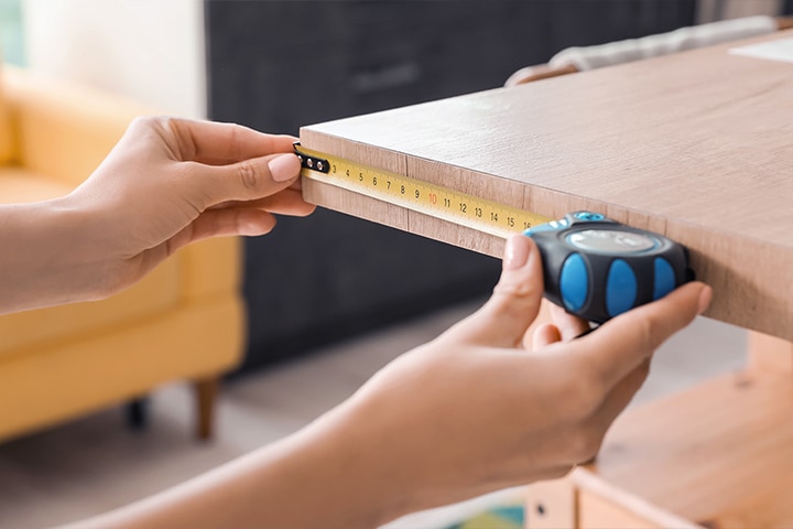 Checking the measurements of the desk with a tape measure	