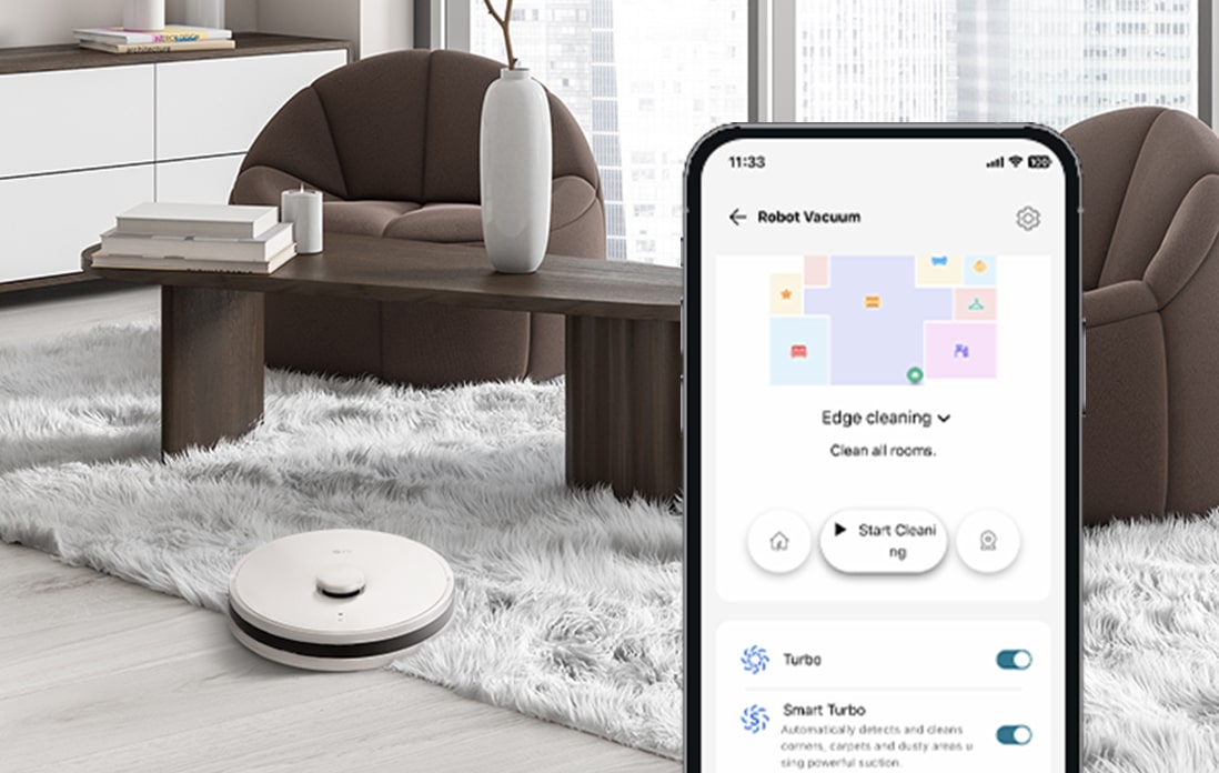 Image of a close-up mobile phone screen and a robot vacuum cleaning the floor and carpet.	