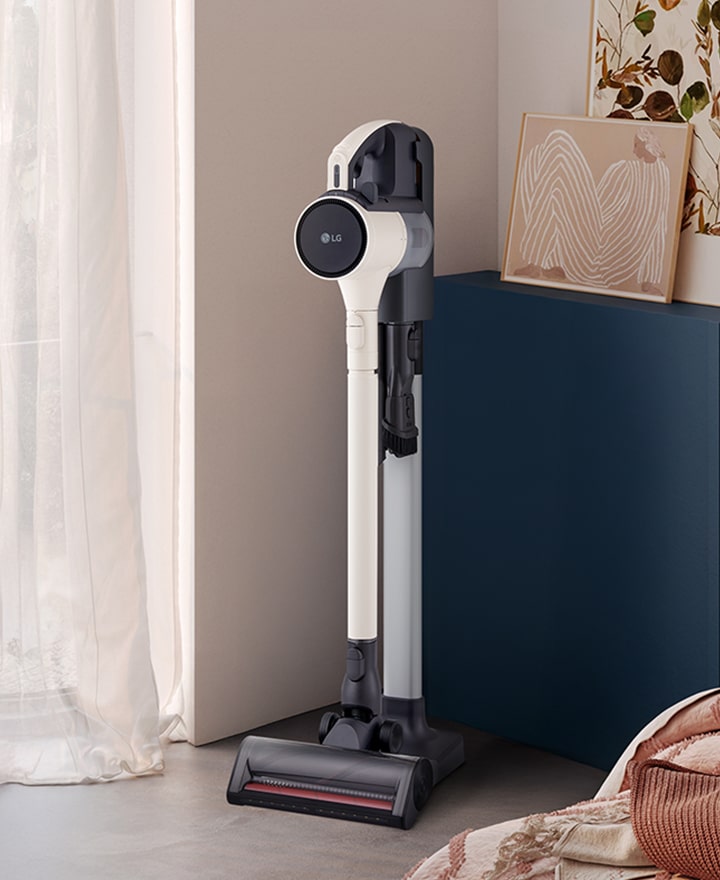 A9L vacuum standing in a bright, stylish living space near a cabinet and sofa.