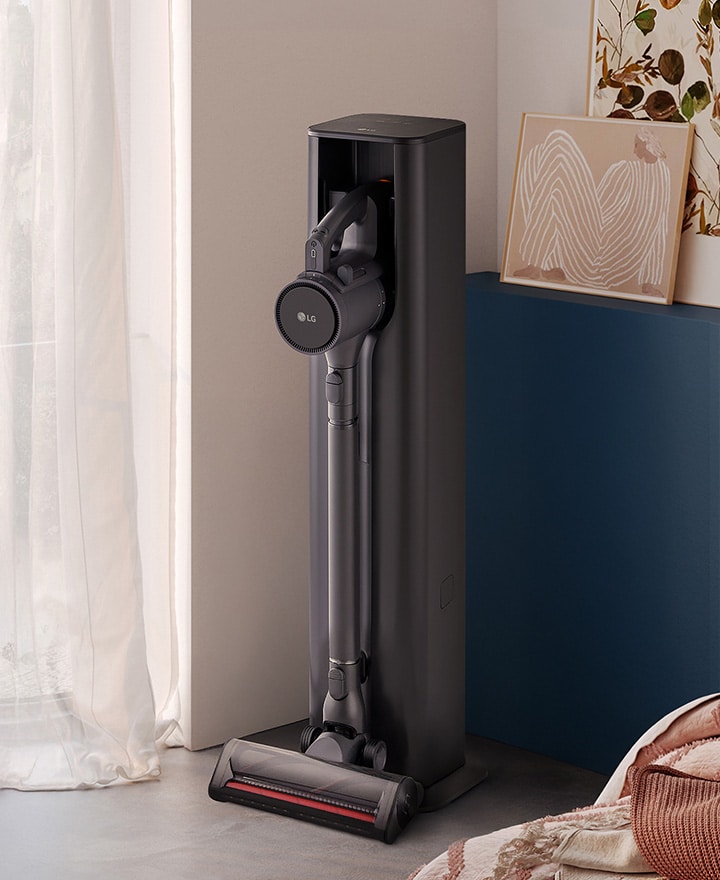 A9L vacuum standing in a bright, stylish living space near a cabinet and sofa.