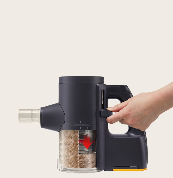 Hand pressing LG A9 Kompressor™ to compress collected dust, showing red arrow indicating compacted bin.