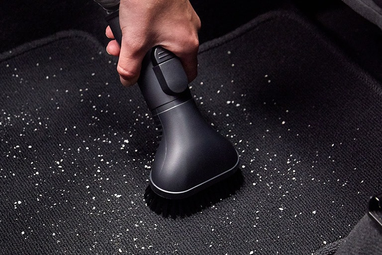 Four images: the first is the hard dirt tool getting dirt from a car carpet, the second is the flexible crevice tool reaching behind a table, the third is the multi angle tool getting dust from a top shelf, and the fourth is the flexible hose extension getting a narrow space in the car.