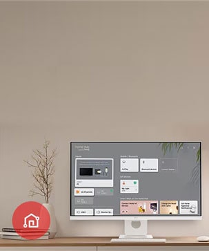 On the table, the monitor displays the Home dashboard screen, with the LG ThinQ App icon visible in the bottom left corner.