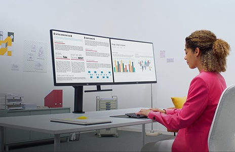 woman works at desk on ergo monitor reviewing documents