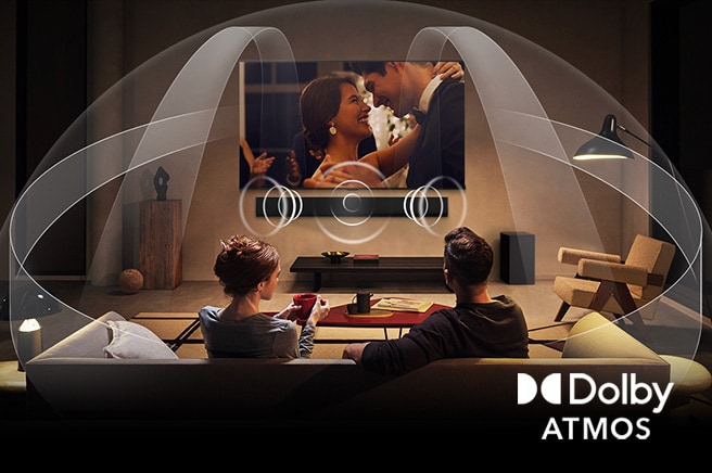 Sala de estar acogedora y poco iluminada con una pareja viendo una película en su televisor LG OLED con barra de sonido LG. Los gráficos muestran cómo Dolby Atmos llena todo el espacio con sonido envolvente desde todas las direcciones. El logotipo de Dolby Atmos se encuentra en la esquina inferior.