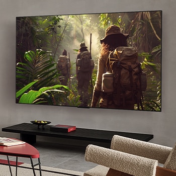 Wide view of a living room inside a premium home, a man is watching a movie on his wall-mounted LG OLED TV. The TV's design blends elegantly with the wall and the interior design.