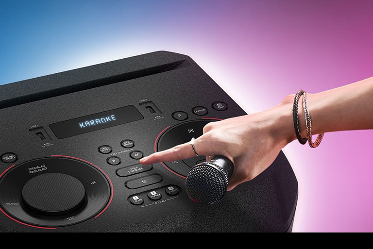 Una mano que sostiene un micrófono intenta presionar el botón de cancelación de voz en la parte superior de LG XBOOM.