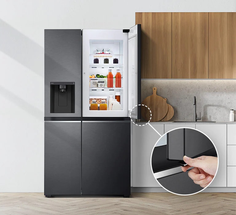 Vista frontal del refrigerador instalado en una cocina. La puerta superior derecha está abierta y hay un círculo y una línea que lleva a un círculo más grande que muestra una vista ampliada del botón en la esquina inferior izquierda de la puerta abierta que tiene un botón de apertura oculto.