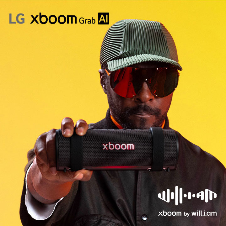 will.i.am, vestido de negro y con lentes de sol, sostiene la xboom Grab en primer plano.