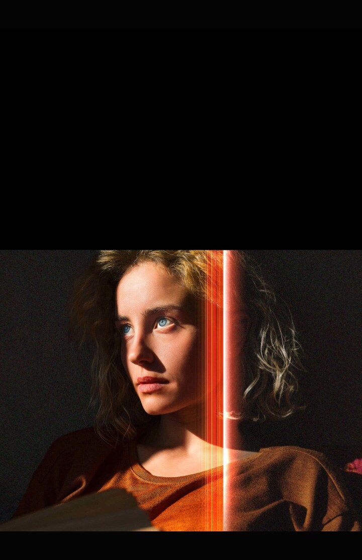 Una mujer con penetrantes ojos azules y un top naranja quemado en un espacio oscuro. Las líneas rojas que representan los refinamientos de la IA cubren parte de su rostro, que es brillante y detallado, mientras que el resto de la imagen parece aburrido.