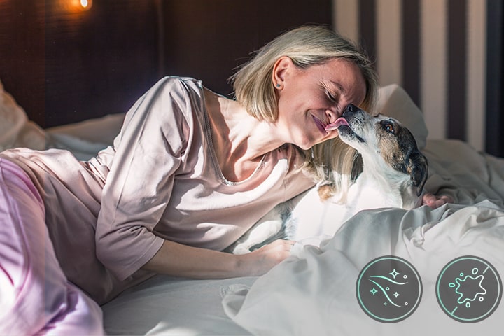 Una mujer y un perrito acostados en una cama