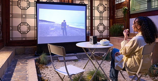 Un huésped ve una película proyectada en una pantalla con CineBeam.