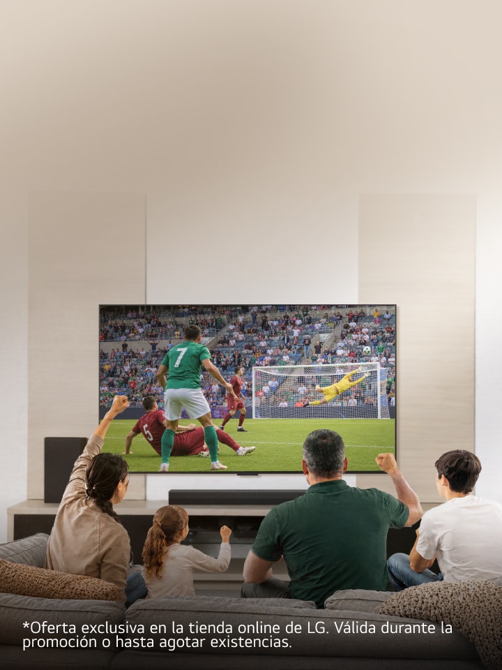Una familia sentada en el sofá de la sala disfruta y celebra un partido de fútbol en una pantalla grande.