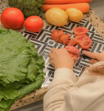Una mamá prepara zanahorias, brócoli, papas y otras verduras para las comidas de su bebé.