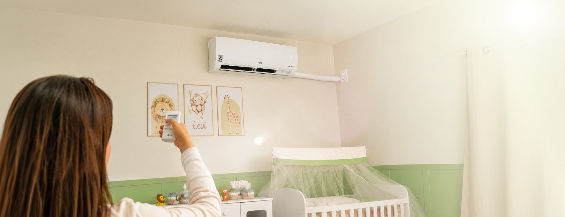 Una mamá ajusta el aire acondicionado LG de pared en la habitación del bebé.