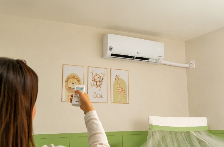 Una mamá ajusta el aire acondicionado LG de pared en la habitación del bebé.