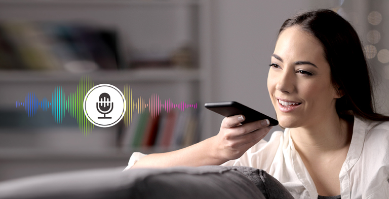 Una mujer controla la televisión hablando con un mando a distancia con reconocimiento de voz.