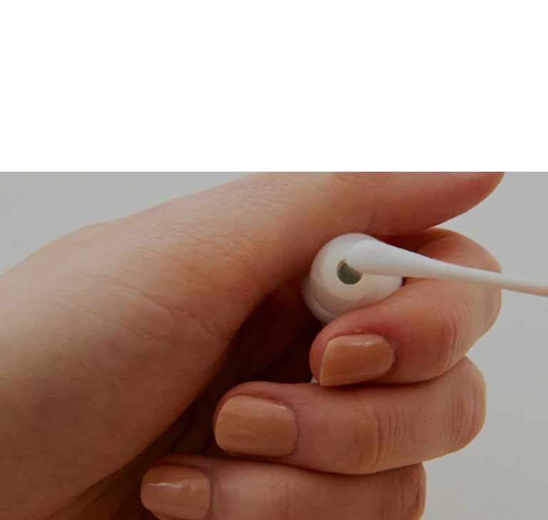 Una imagen de sostener los auriculares en la mano y limpiarlos con un hisopo de algodón, expresando la gravedad de las bacterias contenidas en los auriculares.