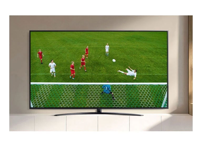 La pantalla de un televisor reproduce un video de un jugador de fútbol haciendo un gol durante un partido de fútbol. (reproducir el video)