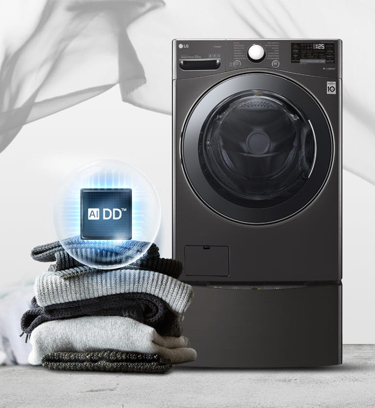 Una lavadora negra se encuentra de frente, con una pila de suéteres y mantas a la izquierda y el logotipo de la AIDD con un círculo azul claro alrededor en la parte superior