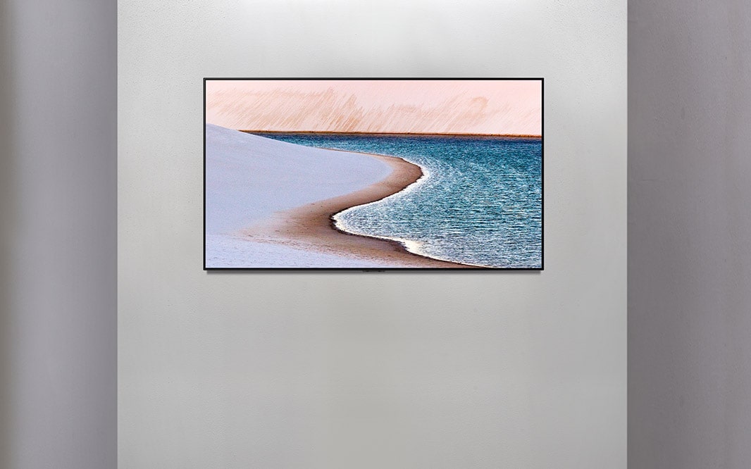 TV en una pared que muestra una imagen de la orilla del mar.
