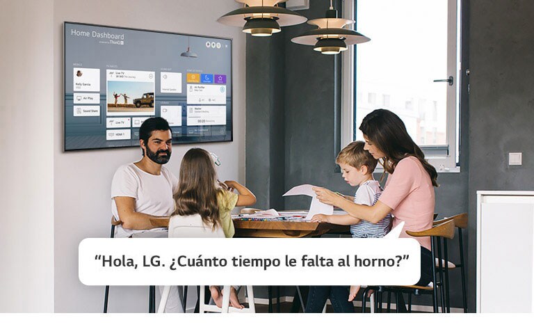 Familia sentada en una mesa con la madre preguntándole a la TV el tiempo restante del horno