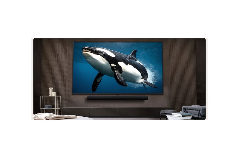 LG TV con una pantalla impresionantemente grande montada en una pared encima de una LG Soundbar en una sala de estar de estilo moderno.
