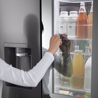 Una persona toca la puerta de una refrigeradora LG para ver el interior sin abrirla, mostrando la tecnología InstaView™.