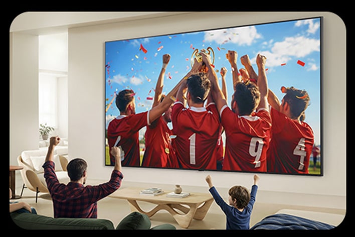 Living room scene with a family cheering while watching a soccer celebration on a very large wall-mounted TV
